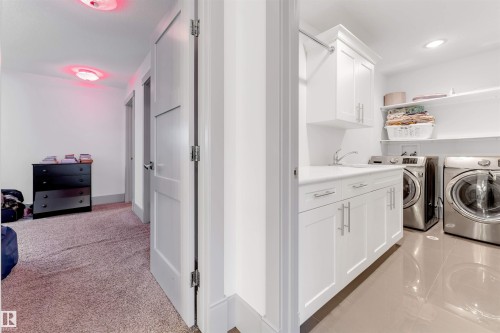 Dedicated laundry area featuring white shaker-style cabinetry, a built-in sink, and integrated shelving - 656 180 Street Sw, Edmonton, AB - Indoor Photo Showing Laundry Room