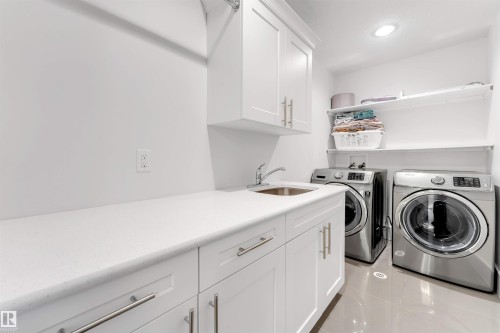Utility room featuring a white countertop with integrated sink, white cabinetry with brushed nickel hardware, and overhead recessed lighting - 656 180 Street Sw, Edmonton, AB - Indoor Photo Showing Laundry Room