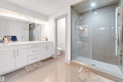 Contemporary bathroom featuring a spacious glass-enclosed shower, a double vanity with white cabinetry, and large format floor tiles - 656 180 Street Sw, Edmonton, AB - Indoor Photo Showing Bathroom
