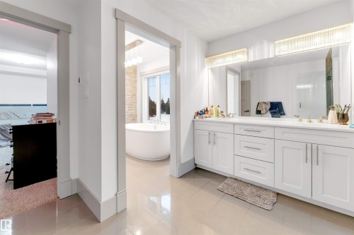 Dual vanity with white cabinetry and integrated sinks, illuminated by two linear light fixtures - 656 180 Street Sw, Edmonton, AB - Indoor Photo Showing Bathroom