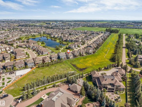 Aerial perspective showcasing a residential community with a central pond feature - 656 180 Street Sw, Edmonton, AB - Outdoor With View