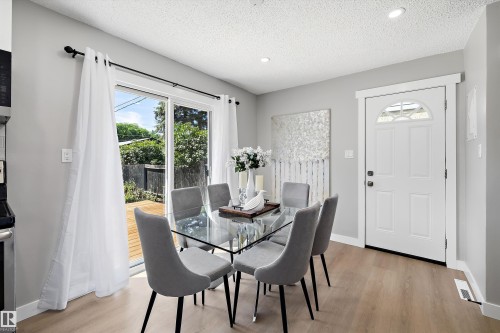 Dining area featuring wood-finish flooring, recessed lighting, and a white entry door with an arched transom window - 12912 103 Street, Edmonton, AB 