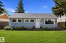 Single-story residence featuring light blue siding with white trim, a gray shingle roof, and a prominent front door with a decorative glass insert - 12912 103 Street, Edmonton, AB 