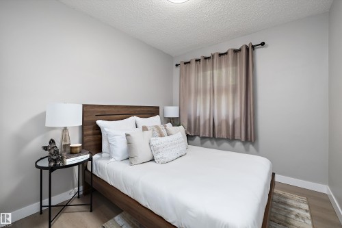 Bedroom featuring wood-finish flooring, light gray wall paint, and a textured ceiling - 12912 103 Street, Edmonton, AB 