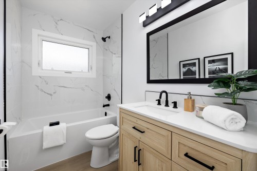 Contemporary bathroom featuring a light wood-finish vanity with a white countertop and rectangular undermount sink - 12912 103 Street, Edmonton, AB 