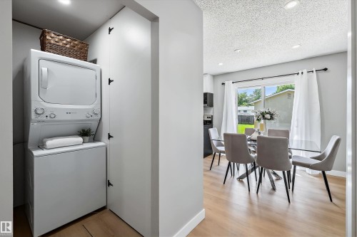 Dedicated laundry closet featuring a stacked washer and dryer, wood-finish flooring, and recessed lighting - 12912 103 Street, Edmonton, AB 