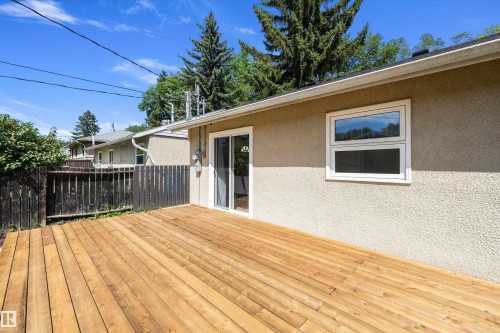 Expansive wood deck with a stucco exterior, sliding glass door, and white frame window - 12912 103 Street, Edmonton, AB 