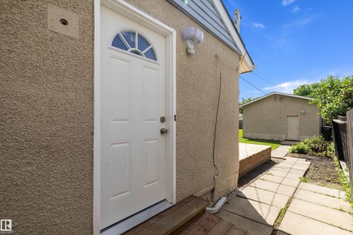 White paneled door with arched window detail, stucco exterior, and wood steps - 12912 103 Street, Edmonton, AB 