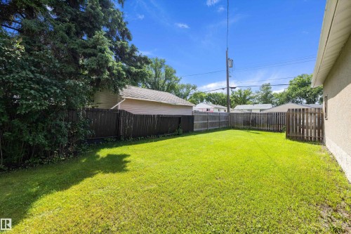Expansive backyard featuring a lush green lawn, full privacy fencing, and mature perimeter landscaping - 12912 103 Street, Edmonton, AB 