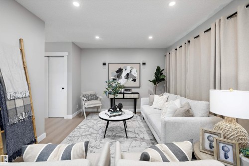 Recessed ceiling lighting, light wood-finish flooring, a contemporary white door, and white baseboards define this living space - 12912 103 Street, Edmonton, AB 