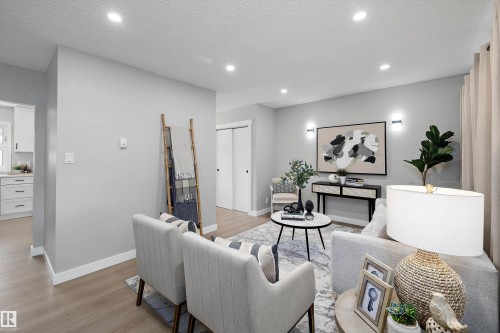 Open-concept living space featuring recessed ceiling lighting, light wood-finish flooring, and crisp white baseboards - 12912 103 Street, Edmonton, AB 