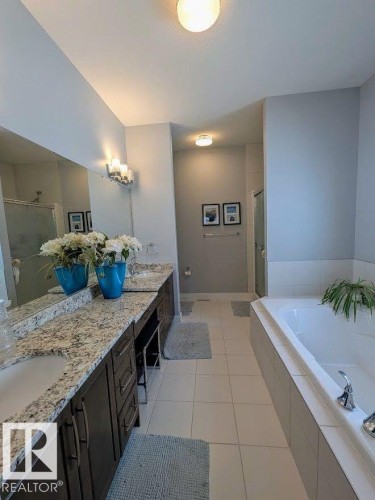 Spacious bathroom featuring a dual vanity with granite countertops, undermount sinks, and dark wood cabinetry - 2327 Frezenberg Avenue, Edmonton, AB 