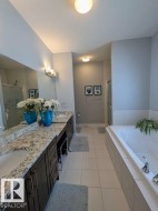 Spacious bathroom featuring a dual vanity with granite countertops, undermount sinks, and dark wood cabinetry - 