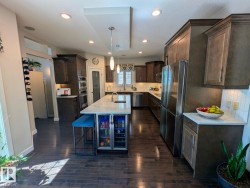 Contemporary kitchen featuring wood-finish flooring, recessed lighting, and a spacious island with a built-in beverage cooler - 