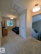 Carpeted upper-level landing featuring a skylight, flush-mount lighting, a paneled door, and a staircase - 