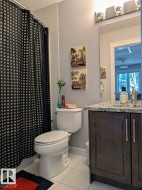 Bathroom featuring a dark wood-finish vanity with a granite countertop, white ceramic toilet, and tiled flooring - 