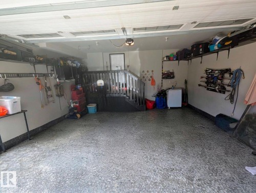 Spacious garage featuring a durable epoxy floor, integrated overhead shelving, slatwall organization, and interior staircase access - 2327 Frezenberg Avenue, Edmonton, AB 