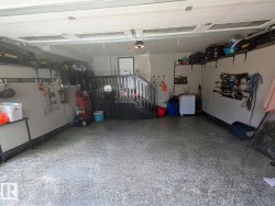 Spacious garage featuring a durable epoxy floor, integrated overhead shelving, slatwall organization, and interior staircase access - 