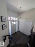 Bright entryway featuring a contemporary crystal chandelier, white panel door with glass sidelights and transom, dark patterned floor tiles, and bi-fold closet doors - 2327 Frezenberg Avenue, Edmonton, AB 