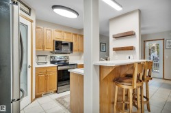 Kitchen featuring wood cabinetry, stainless steel appliances, white countertops, and tile flooring - 