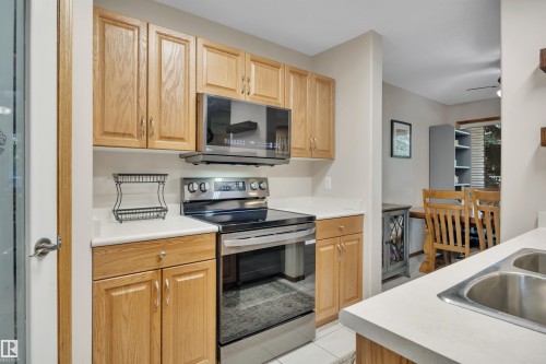 Kitchen featuring wood-finish cabinetry, white countertops, a stainless steel range, and an over-the-range microwave - 207-4807 43A Ave, Leduc, AB 
