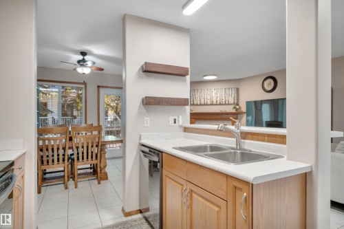Kitchen featuring light wood-finish cabinetry, a double basin stainless steel sink, and light countertops - 207-4807 43A Ave, Leduc, AB 