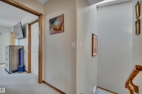 Carpeted hallway with wood trim and white paneled doors - 207-4807 43A Ave, Leduc, AB 