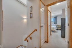 Upper-level hallway featuring light wood-finish trim, white paneled doors, and neutral carpeting - 