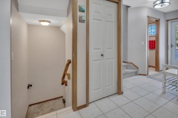Foyer featuring light-toned tile flooring, white bi-fold closet doors, and wood trim accents - 