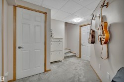 Light gray carpeting extends throughout this interior space, featuring white doors with wood-finish trim and a drop ceiling with recessed lighting - 