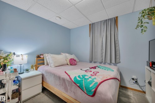 Carpeted bedroom featuring light blue walls and a drop ceiling - 207-4807 43A Ave, Leduc, AB 