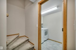 Functional laundry area featuring wood-finish flooring, a contemporary washer and dryer set, and a fluorescent ceiling light fixture - 