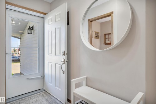 Entryway featuring a paneled door, storm door, and neutral wall paint - 207-4807 43A Ave, Leduc, AB 