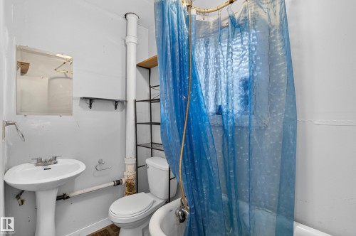 Bathroom featuring a pedestal sink, toilet, and a window - 11708 79 Street, Edmonton, AB 