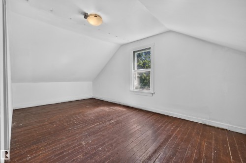 Interior room featuring a single window, sloped ceilings, and wood-finish flooring - 11708 79 Street, Edmonton, AB 