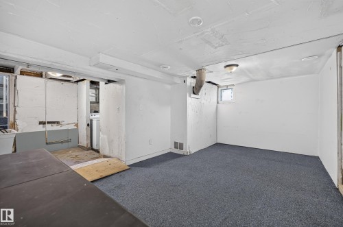 Finished lower-level room featuring blue carpeting, white painted walls, and a small window - 11708 79 Street, Edmonton, AB 