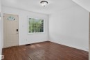 Interior room featuring wood-finish flooring, white walls, and a multi-pane window - 11708 79 Street, Edmonton, AB 