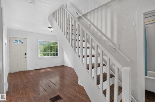 Staircase with white balusters and wood-finish treads, complemented by dark wood-finish flooring - 11708 79 Street, Edmonton, AB 