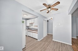 Open concept living space featuring wood-finish flooring, a ceiling fan with integrated lighting, and light blue wall tones - 