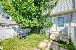 Two-story exterior with siding, a mature tree, concrete entry stairs, and a partial privacy fence - 