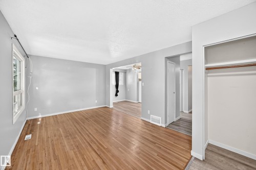Spacious room featuring wood-finish flooring, light gray walls, white trim, and a window for natural illumination - 355 Northgate Terrace, Edmonton, AB 