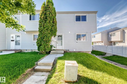 Two-story exterior with light gray siding, white trim, and a prominent evergreen shrub - 355 Northgate Terrace, Edmonton, AB 