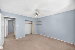 Bedroom featuring light blue walls, brown carpet, a ceiling fan, an open closet with a hanging rod, and two wall-mounted shelves - 