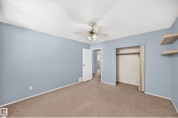 Bedroom featuring light blue walls, a textured ceiling, and brown carpeting - 