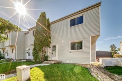 Multi-level townhouse exterior featuring light gray horizontal siding and a sloped roofline - 