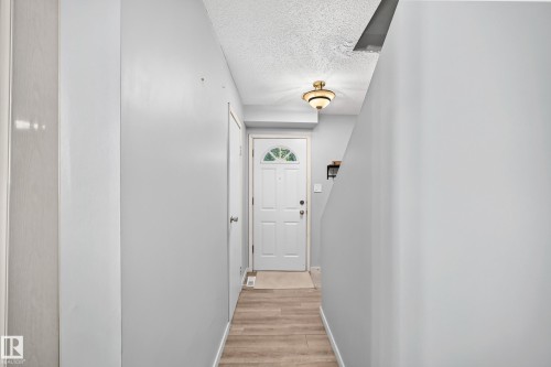 Entryway featuring wood-finish flooring, a white paneled door with an arched window, and a flush-mount light fixture - 355 Northgate Terrace, Edmonton, AB 