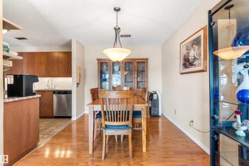 Dining area featuring wood-finish flooring, a decorative chandelier, and a built-in display cabinet - 2324 151 Avenue Nw, Edmonton, AB 