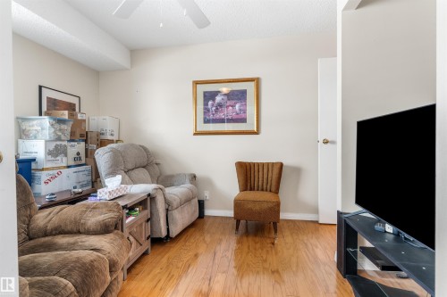 Warm wood-finish flooring complements neutral wall tones and a ceiling fan - 2324 151 Avenue Nw, Edmonton, AB 
