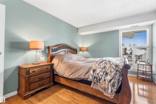 Bright room featuring wood-finish flooring, light blue wall paint, and a large window with white trim - 2324 151 Avenue Nw, Edmonton, AB 