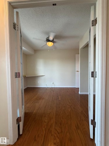 Room with wood-finish flooring, a ceiling fan with light fixture, and a built-in wall shelf - 2324 151 Avenue Nw, Edmonton, AB - Indoor